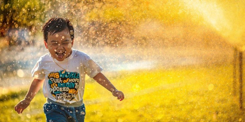 child running through a sprinkler
