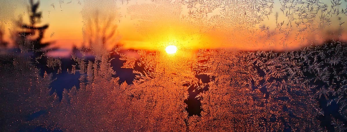 frost on the window with the sunrising outside