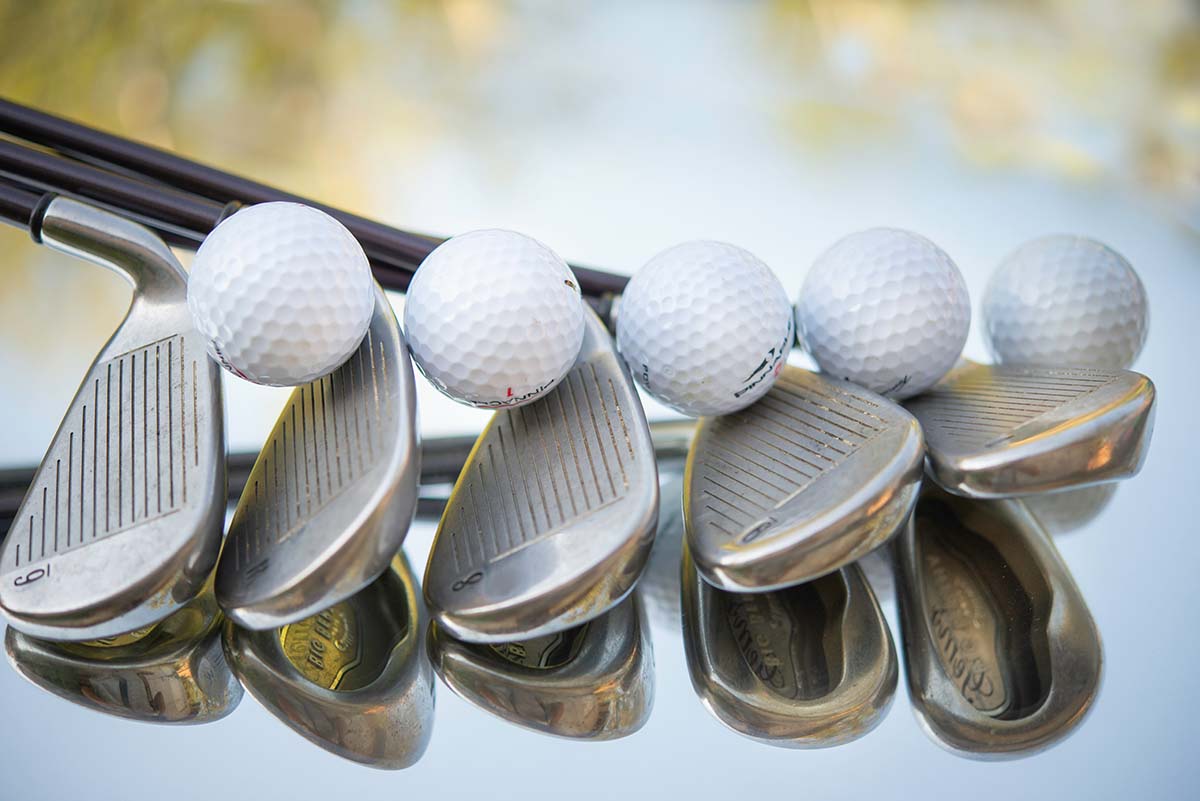 golf-clubs - Low Two Pair Golf balls resting on top of golf clubs.