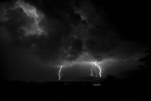 A dramatic thunderstorm forming over a quiet landscape, symbolizing contrast between chaos and calm.