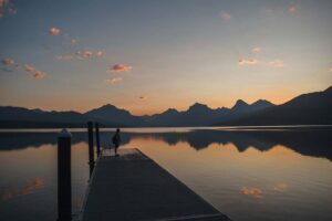 a solitary person standing on a dock at sunrise