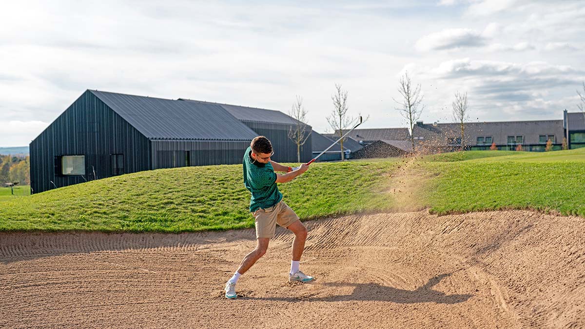 a person hitting out of a bunker on a golf course.