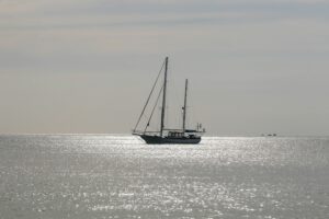 A lone boat floats in the middle of the ocean, symbolizing isolation and perspective from the water.
