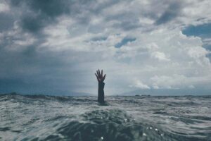a hand sticking out of the water, a person drowning.