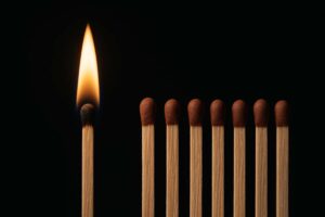A single lit match glowing against unlit matches, symbolizing passion standing out from apathy.