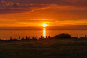 sun setting over the beach with bystanders saying goodbye to summer.