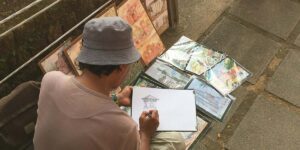 a person sitting on a park bench drawing