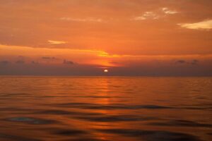 A sunrise over calm water, symbolizing time as a gift and the quiet pursuit of happiness.