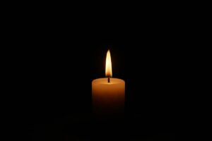 a single candle shining in the dark