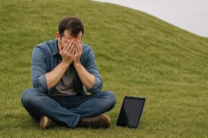 a man crying into his hands over an iPad