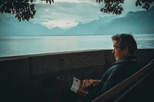 a man sitting quietly holding a book and watching the mountains