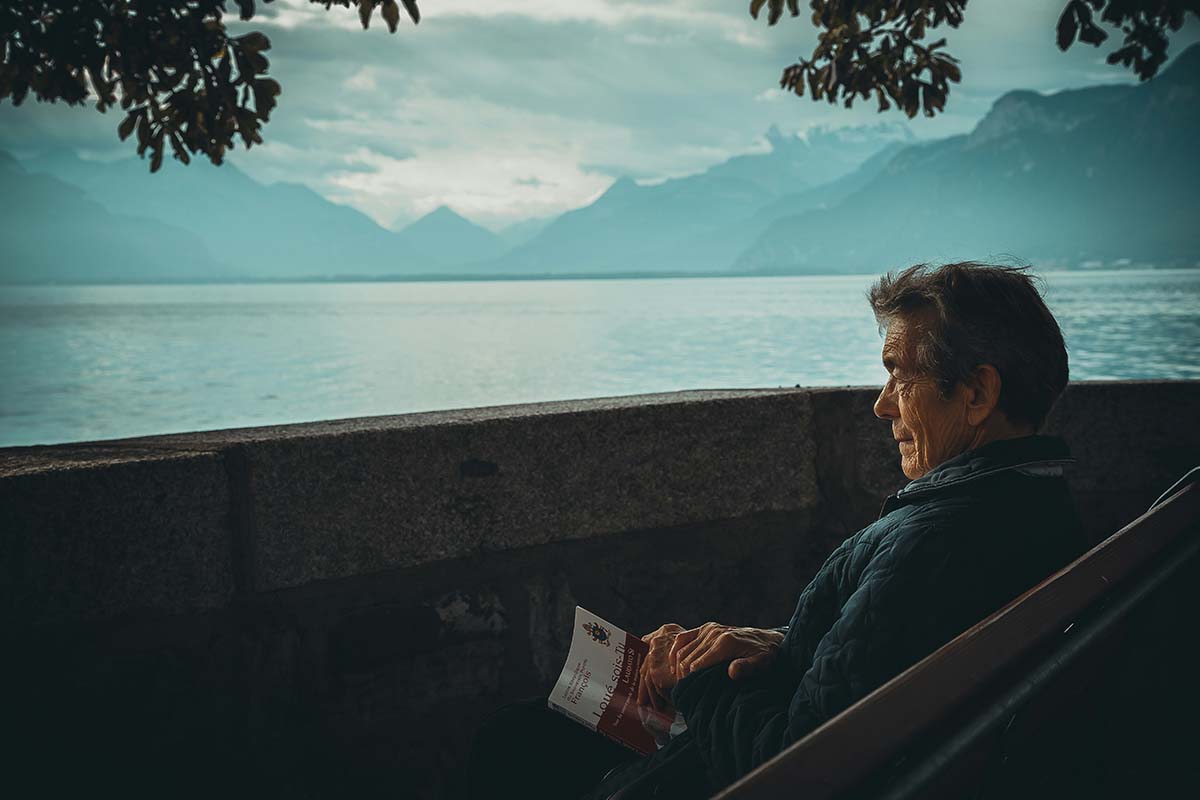 a man sitting quietly holding a book and watching the mountains