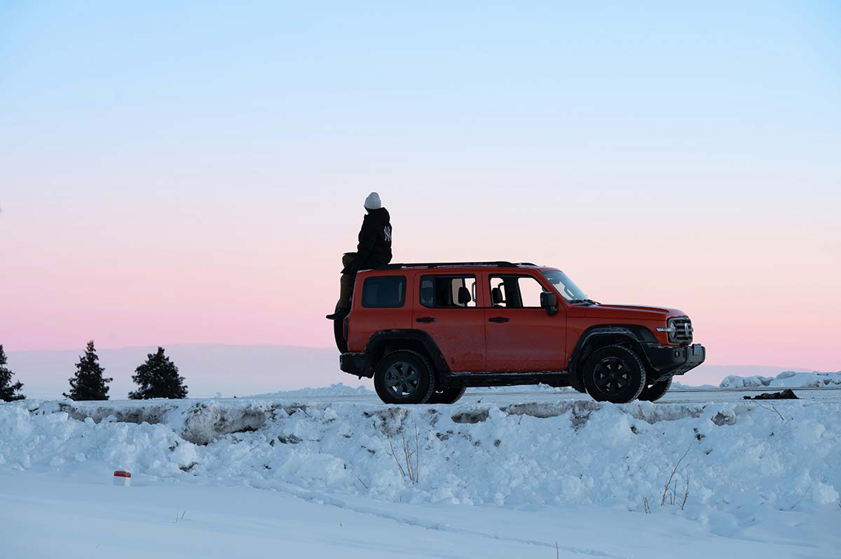 a car stranded in the snow with a person sitting on top