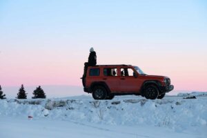 a car stranded in the snow with a person sitting on top