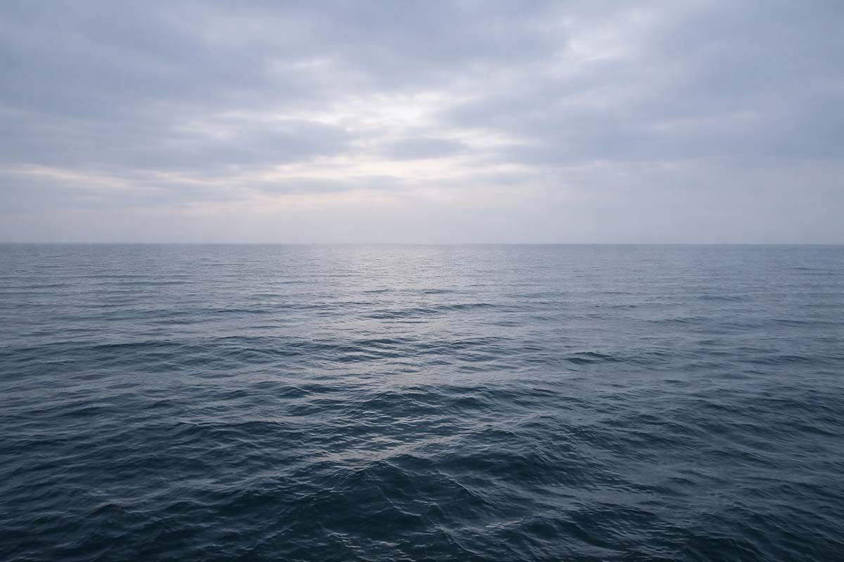 Open water beneath a gray winter sky with a distant horizon, suggesting a moment of pause before decisive action.