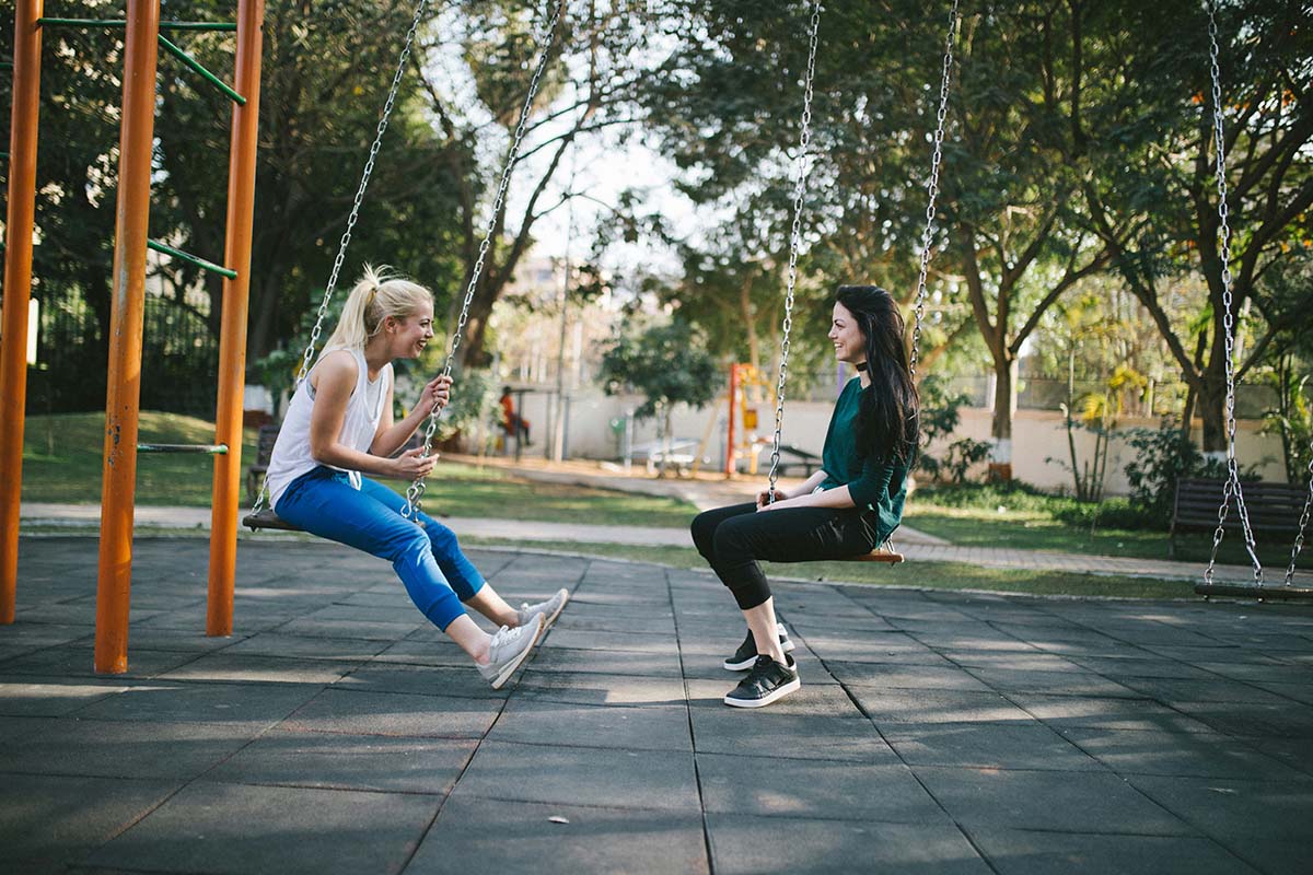 two people swinging in the park
