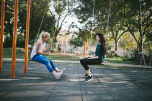 two people swinging in the park